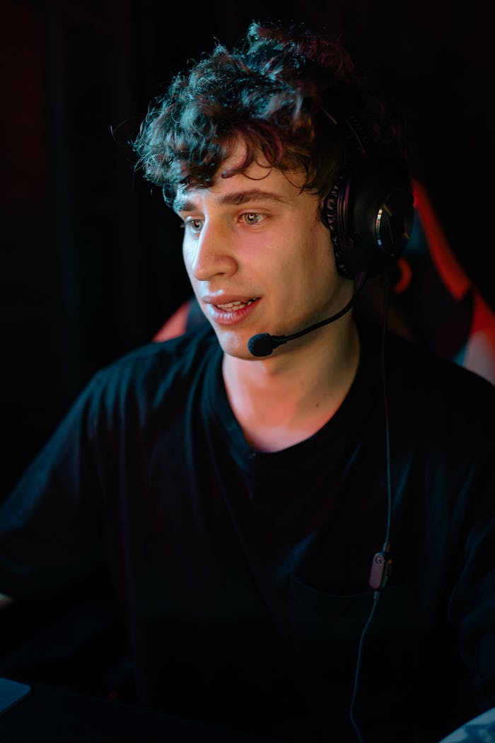 A focused young man with a headset engaged in gaming, immersed in the digital world.